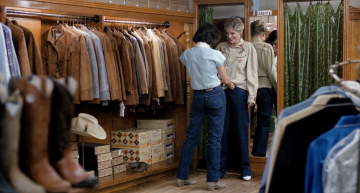 a still from the movie Desert Hearts, in which a brunette lesbian helps a blonde woman buy her first button-up ;)